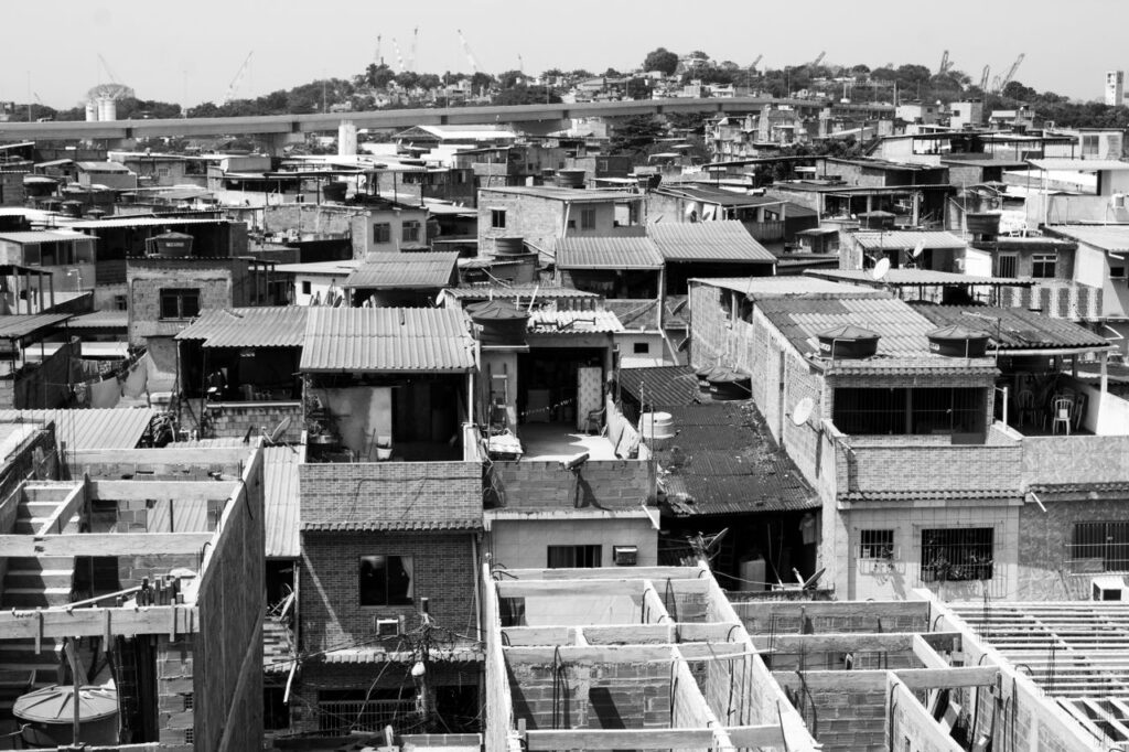 A high-angle black and white view of a densely packed urban neighborhood with unfinished rooftops.
