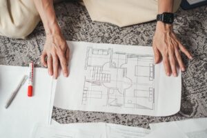 Hands on a detailed architectural floor plan paper, showcasing home design layout.
